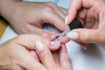 woman hand on manicure treatment with cuticle knife in beauty salon. applying a brush on acrylic nails in the salon