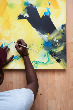 Artist painting abstract canvas with paintbrush.