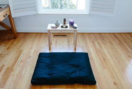 View of a meditation cushion and shrine in front of a window
