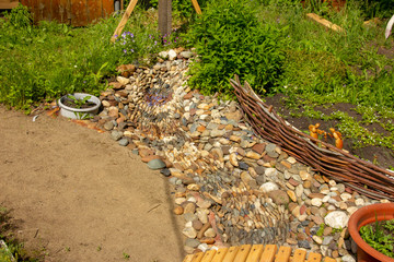 Dry creek in the garden of stones. grass and flowers grow along the bank of the brook.
