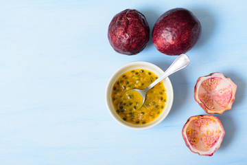 Fresh passion fruit and juice in a bowl with spoon, top view