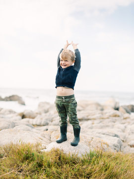 Young boy reaching upwards on beach