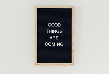 Good Things are Coming"" written on a letterboard hanging on the wall