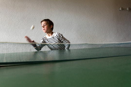 boy reaching to catch a bal at ping pong game.