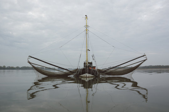 Old wooden fishing boat with two extension arms with trawling nets