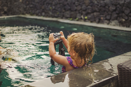 Little girl using underwater video camera in pool