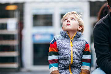 child looking up in awe at city skyscrapers
