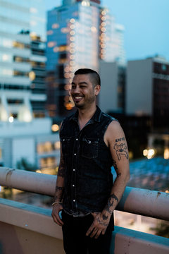 male with tattoos on rooftop smiling