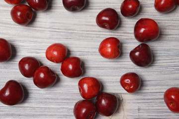Fototapeta na wymiar Red sweet cherry scattered on a white wooden table