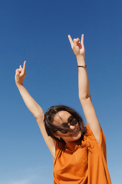 Smiling young Asian woman?showing horns?gesture