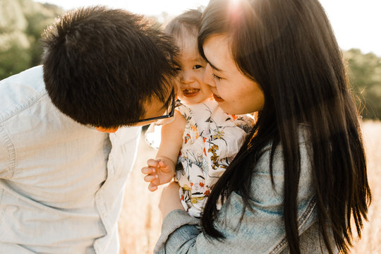 Happy Asian Family Snuggling, Cuddling and being Playful Outdoors