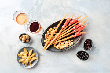 Italian antipasti. Grissini with wine glasses, prosciutto di parma and roasted almonds, with olives...
