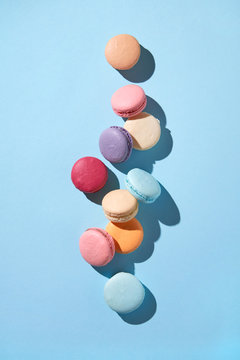 Top view of different multicolored macaroons on a blue backgroun