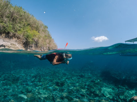 split shot of a young boy snorkeling above a reef in Indonesia