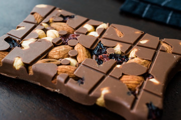 Bluberry Milk Chocolate Bar with Almond, Nuts and Raisin on Wooden Board.