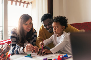 Happy multiethnic family having fun and drawing at home.