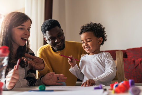 Happy multiethnic family having fun and drawing at home.
