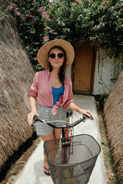 a girl near a villa stands with a bicycle and is going for a walk