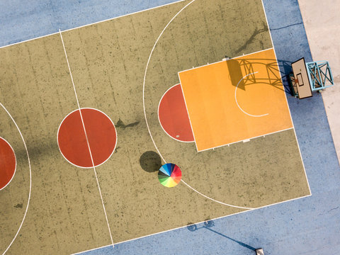 Person with colored umbrella on a  basketball court