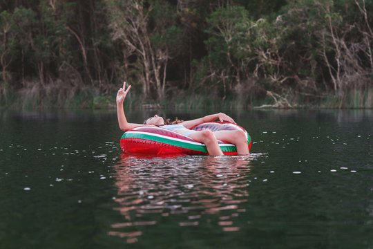 young teen floating on a blow up tyre tube on a lake