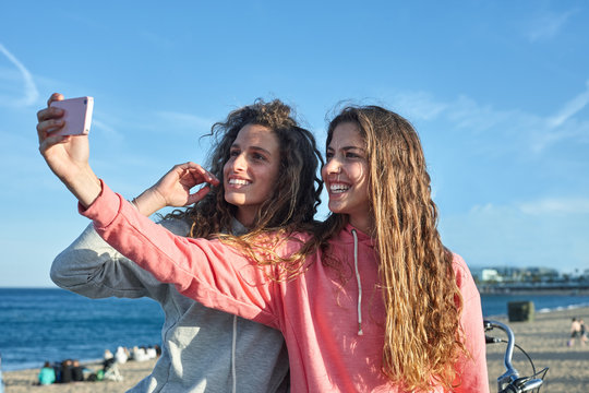 Two young woman taking a selfie by the beach