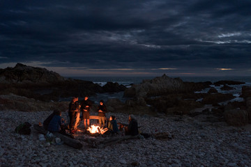 Friends around a beach campfire.