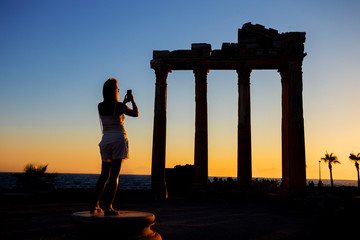 Obraz premium Silhouette of girl photographing on phone Temple of Apollo at sunset