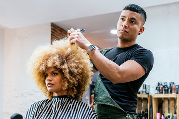 Beautiful afro woman getting haircut by hairdresser in the beauty salon