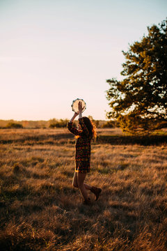 Unrecognizable hippie woman with	tambourine outdoors
