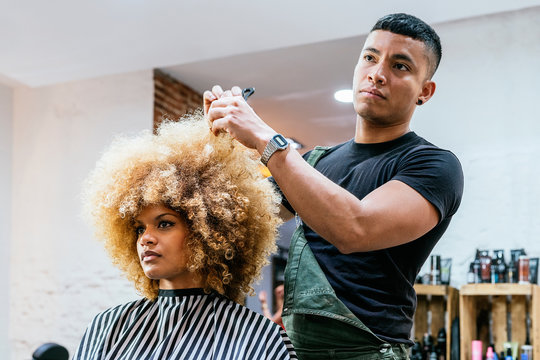 Beautiful afro woman getting haircut by hairdresser in the beauty salon