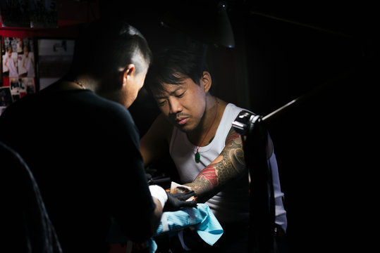 Professional asian tattooer makes a tattoo