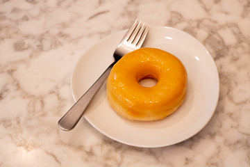 The focus on the edible sugar-donut comes with a stainless steel fork on a beautiful marble table. With space for decorating messages
