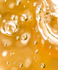 Bubbles of air on the smooth surface of golden water as an abstract background
