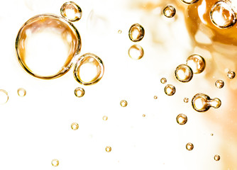 Bubbles of air on the smooth surface of golden water as an abstract background