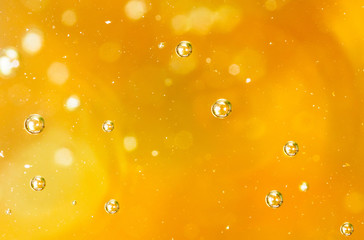 Bubbles of air on the smooth surface of golden water as an abstract background