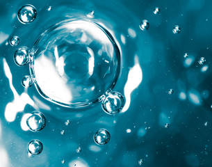 Bubbles of air on the smooth surface of blue water as an abstract background