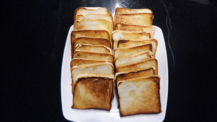 A bunch of  toasted buttered bread on a white plate 