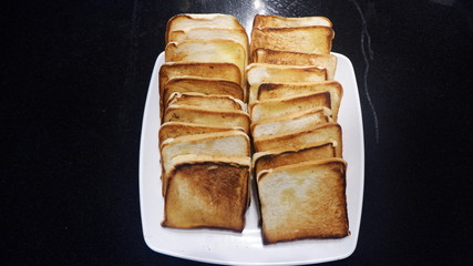A bunch of  toasted buttered bread on a white plate 