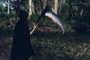 Woman horror ghost holding reaper in forest