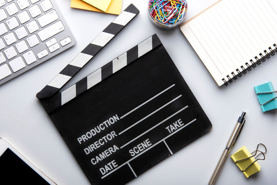 Movie clapper with office stuff the white table top view shot.