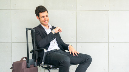 business man is sitting on chair waiting for business trip travel with suitcase and looking at...