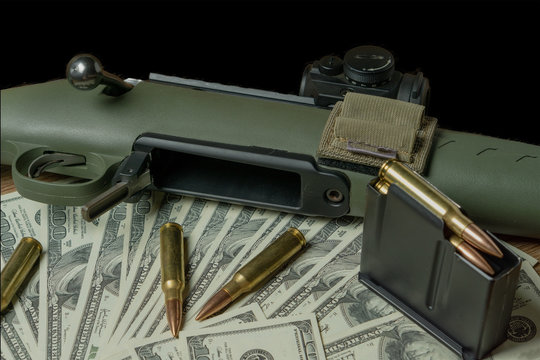 Rifle, magazine and cartridges on hundred dollar bills. Concept for crime, contract killing, paid assassin, terrorism, war, global arms trade, weapons sale. Illegal hunting, poaching