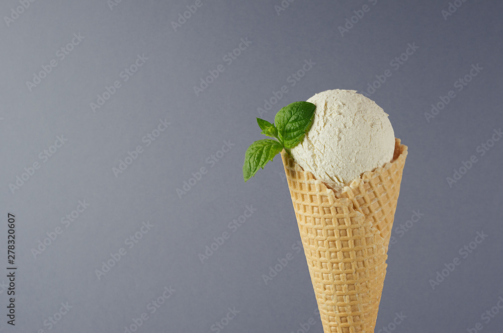 Wall mural classic white creamy ice cream in crisp waffle cone decorated green mint leaf on grey background, cl