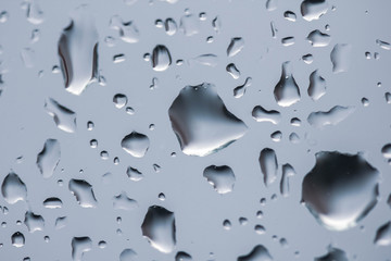 The texture of rain drops on the glass close-up. Macro transparent water drops on white background.