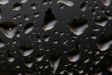 The texture of rain drops on the glass close-up. Macro transparent water drops on dark background.