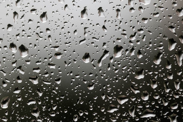 The texture of rain drops on the glass close-up. Macro transparent water drops on dark background.