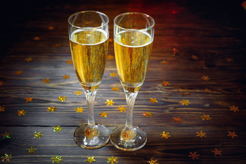 Two glasses of champagne on wooden table in New Year's Eve with bright glitter