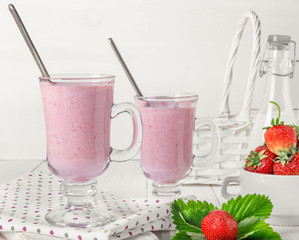 Glass of fresh strawberry and yogurt smoothie on white wooden table