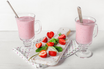 Glass of fresh strawberry and yogurt smoothie on white wooden table