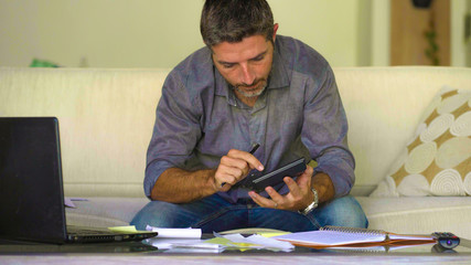 young attractive and busy man at living room sofa couch accounting monthly expenses and debt...